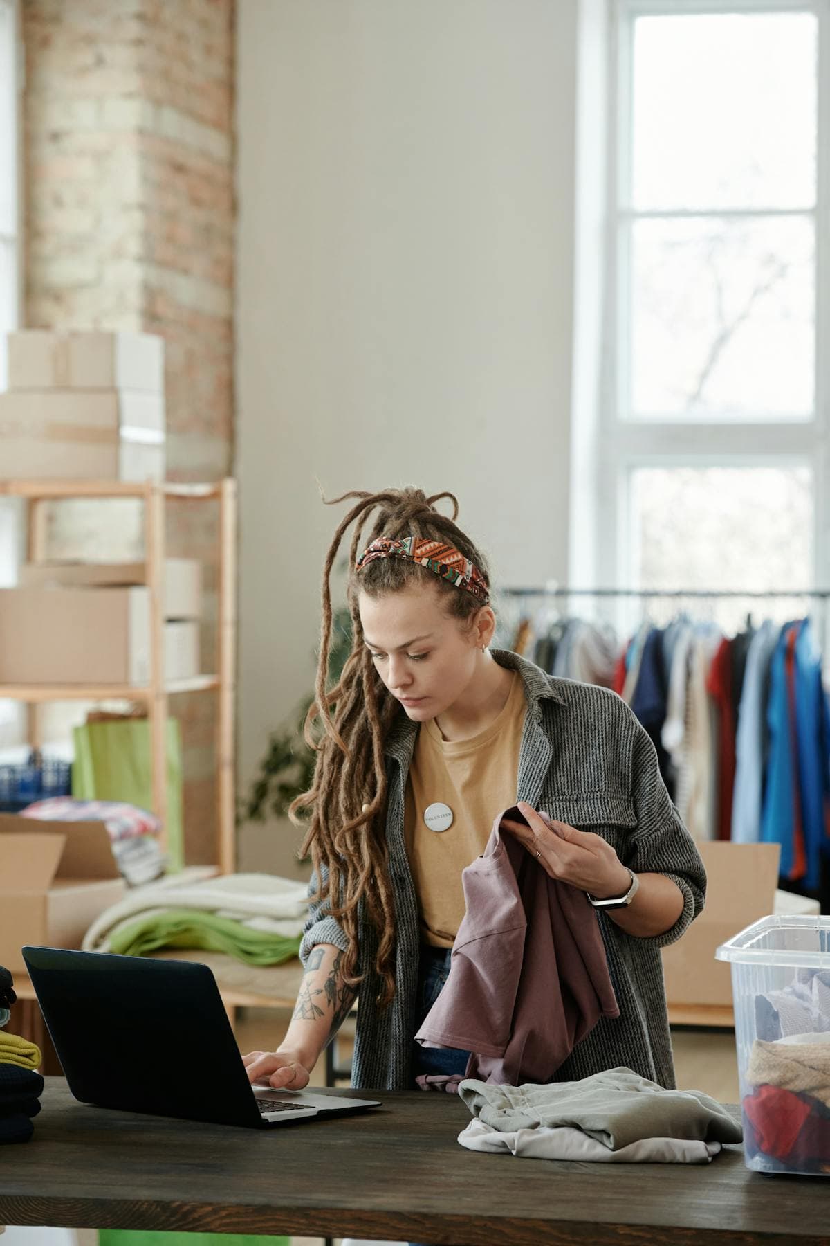 Femme utilisant un ordinateur portable avec un vêtement à la main