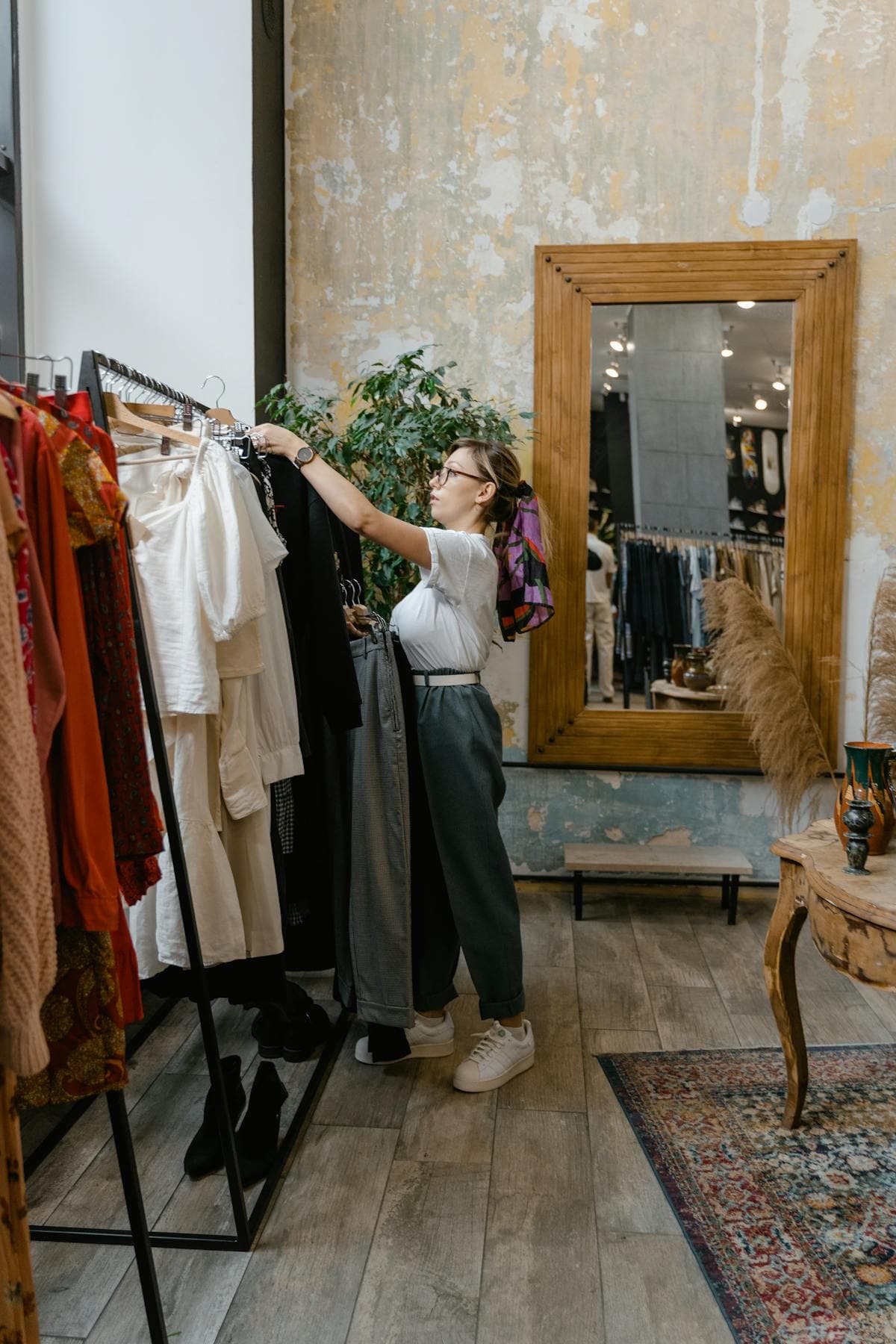 Femme réorganisant des vêtements sur un portant